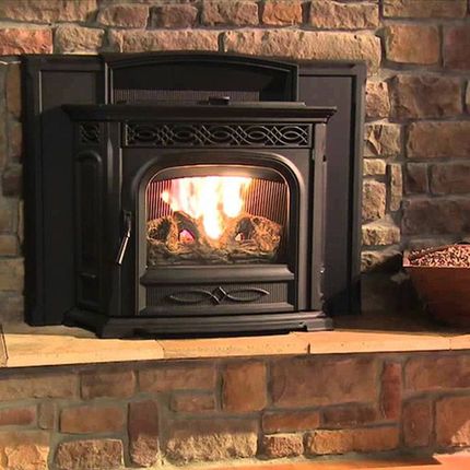 Lit black wood stove with a fire burning in a stone fireplace