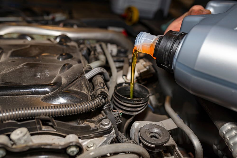 A Person is Pouring Oil Into a Car Engine — SVS Auto Repairs & Dyno Tuning in Bungalow, QLD