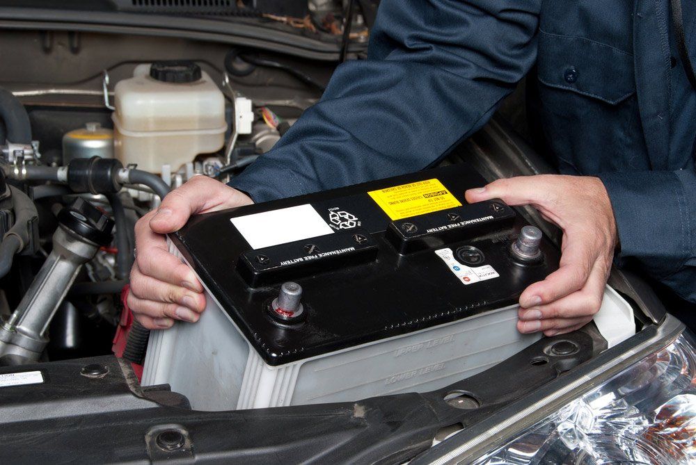 A Man is Holding a Car Battery in His Hands — SVS Auto Repairs & Dyno Tuning in Bungalow, QLD