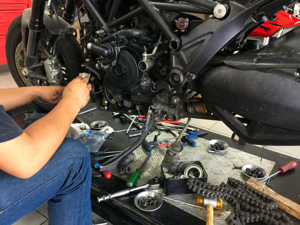 A Man is Working on a Motorcycle in a Garage — SVS Auto Repairs & Dyno Tuning in Bungalow, QLD