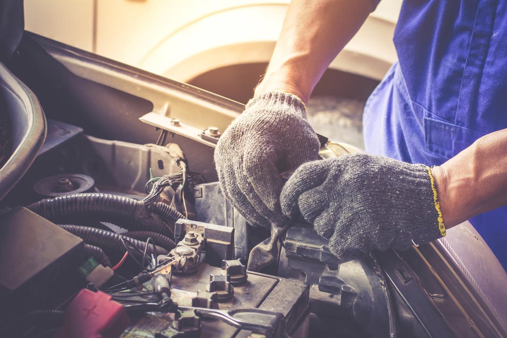 A Man Wearing Gloves is Working on the Engine of a Car — SVS Auto Repairs & Dyno Tuning in Weipa, QLD