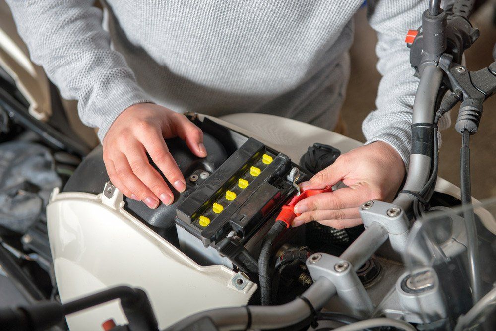 A Person is Installing a Battery on a Motorcycle — SVS Auto Repairs & Dyno Tuning in Bungalow, QLD