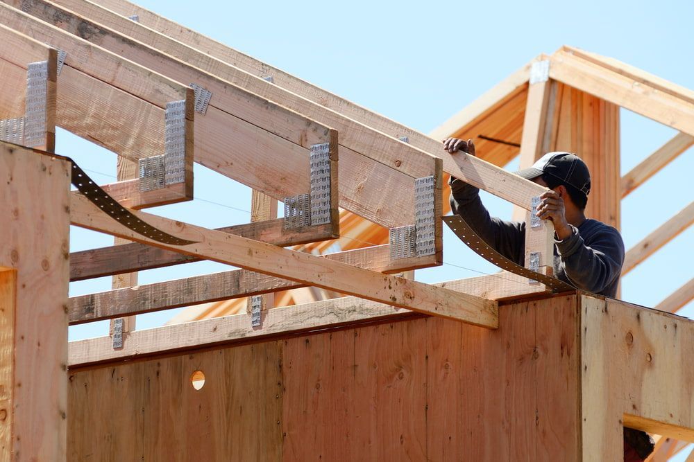A Man Is Working On The Roof Of A House Under Construction — Hitek Frame & Truss In Forbes, NSW