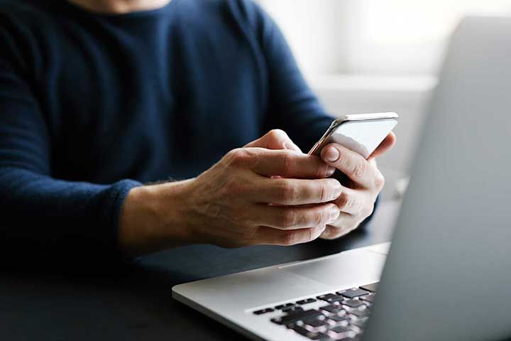 Man with mobile phone and laptop in office