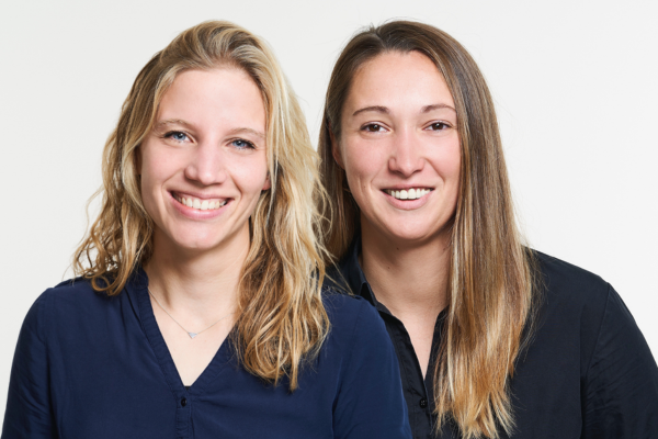 Two smiling people in dark tops against a white background