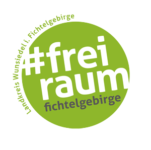 Grünes, kreisförmiges Logo mit weißem Text „#frei raum“ und „Fichtelgebirge“ am Rand