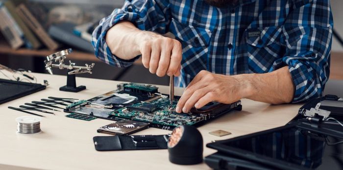 A man in a plaid shirt is working on a laptop computer.