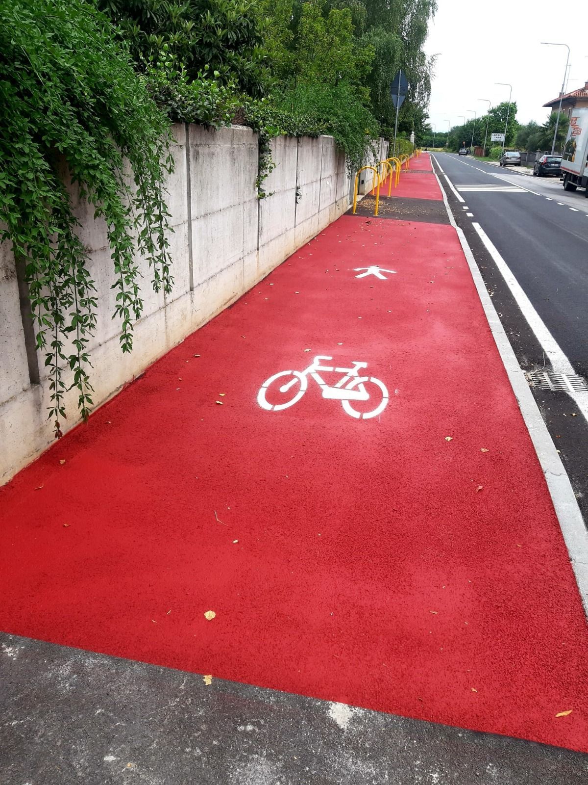 Pista ciclabile rossa con il simbolo bianco della bicicletta e il simbolo del pedone.
