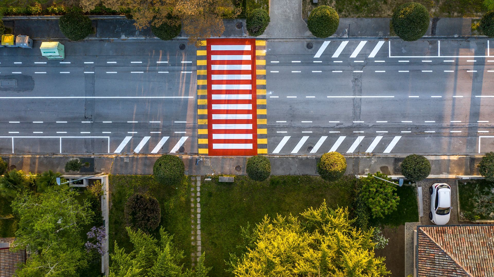 Vista dall'alto di una strada con attraversamento pedonale rosso e bianco. 