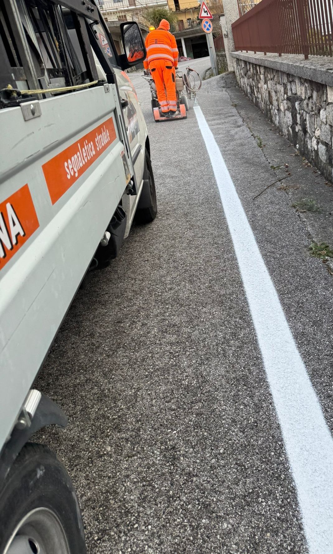 Operaio che dipinge le linee bianche su strada