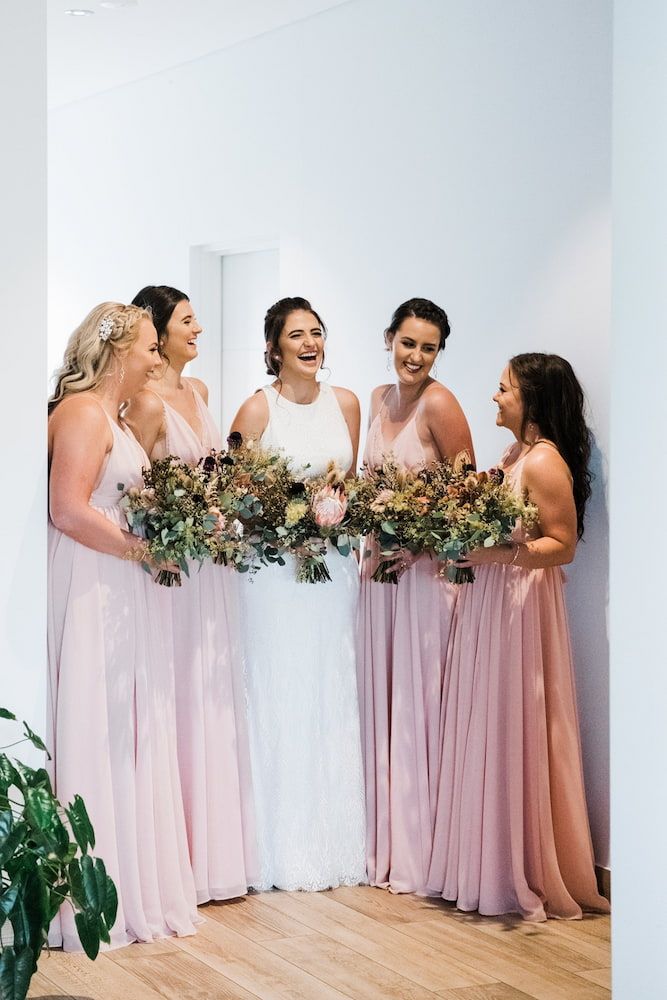 A Group of women in gowns holding flowers and laughing— Just Formals in Winnellie, NT