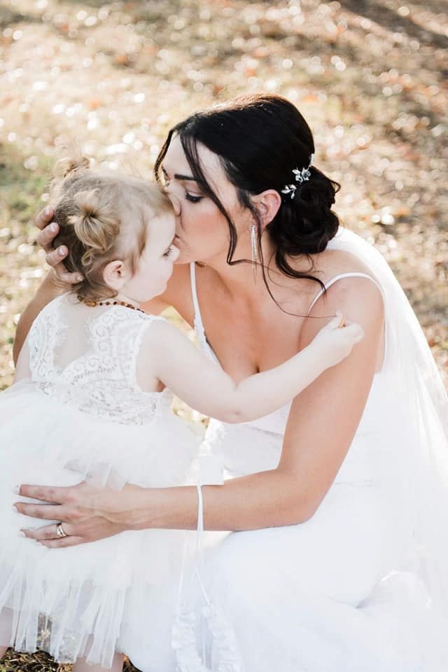A Bride is Kissing Her Flower Girl on the Cheek — Just Formals in Winnellie, NT