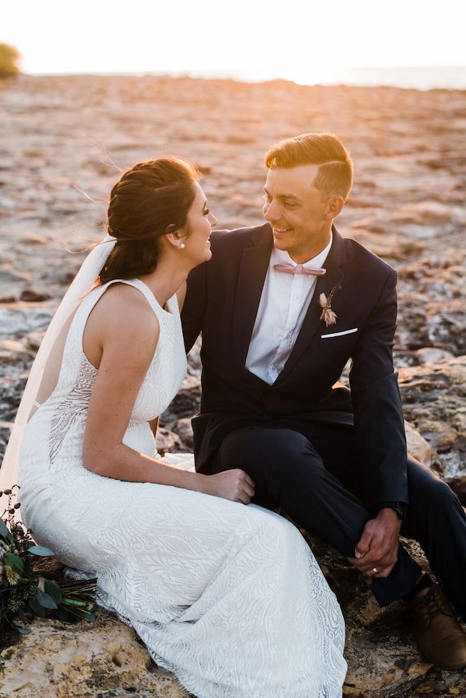 A Bride and Groom Are Sitting on a Rock on the Beach — Just Formals in Winnellie, NT