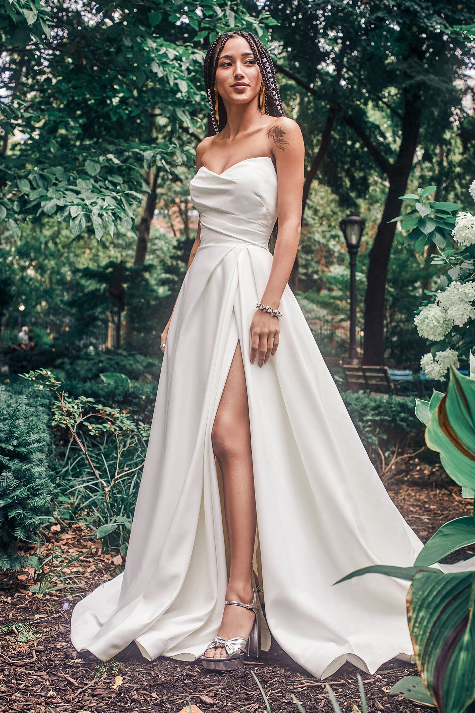 A Woman in a White Gown Stands Confidently in a Lush Garden — Just Formals in Winnellie, NT
