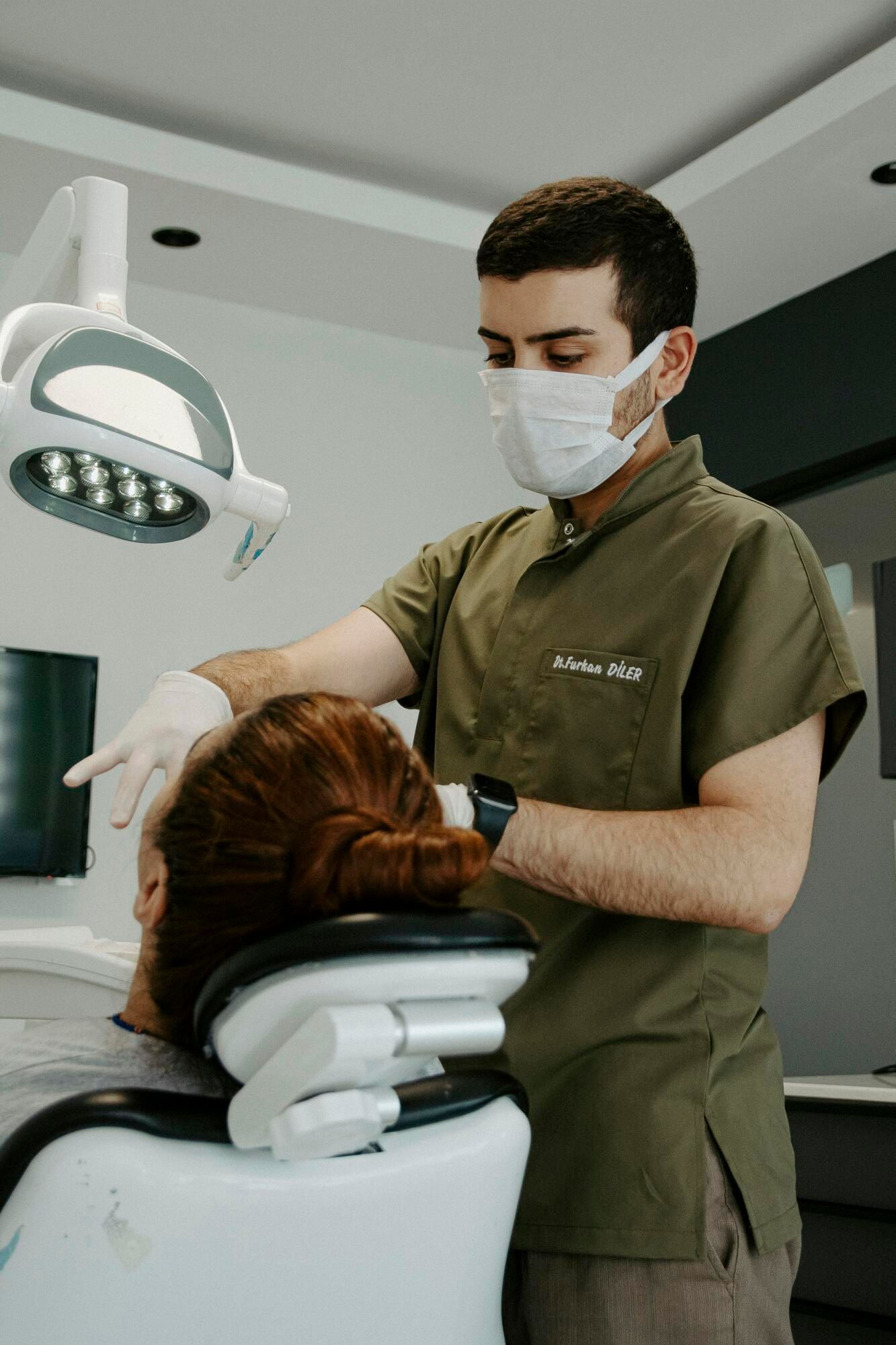 A dentist is examining a patient 's teeth in a dental office.