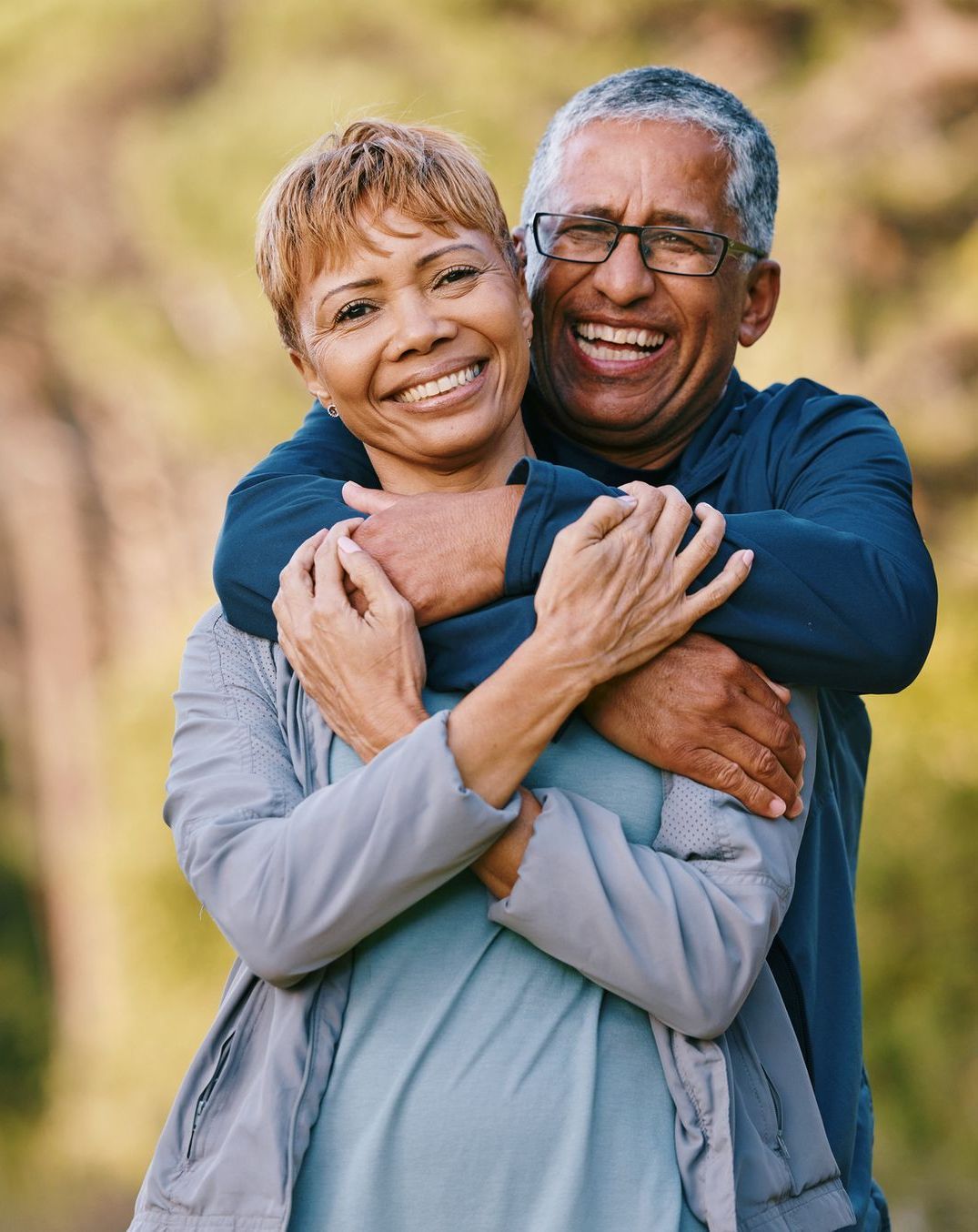 A man and a woman are hugging each other and smiling.