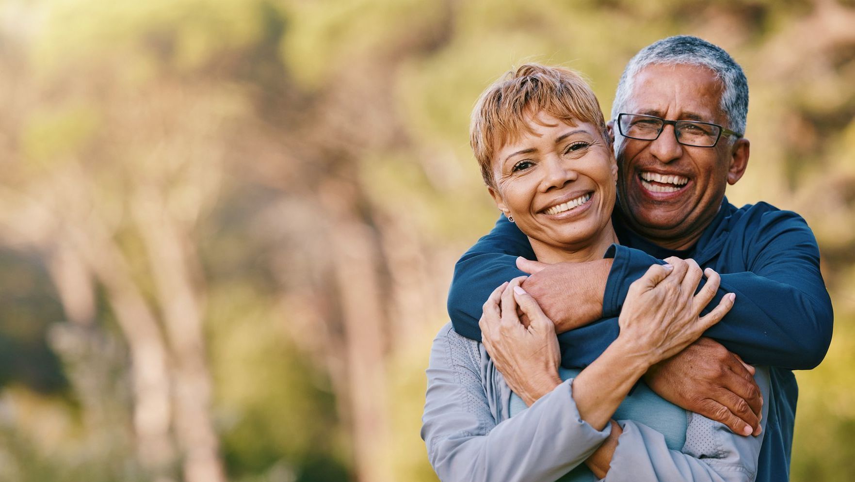 A man and a woman are hugging each other in a park.
