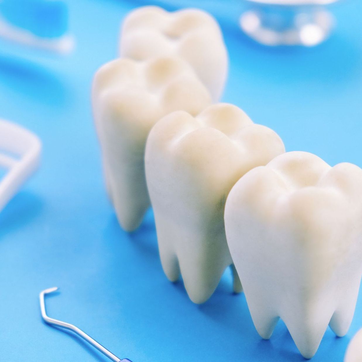 A row of white teeth are lined up on a blue surface.