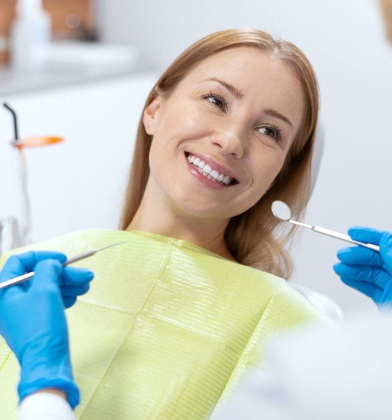 A woman is smiling while having her teeth examined by a dentist.