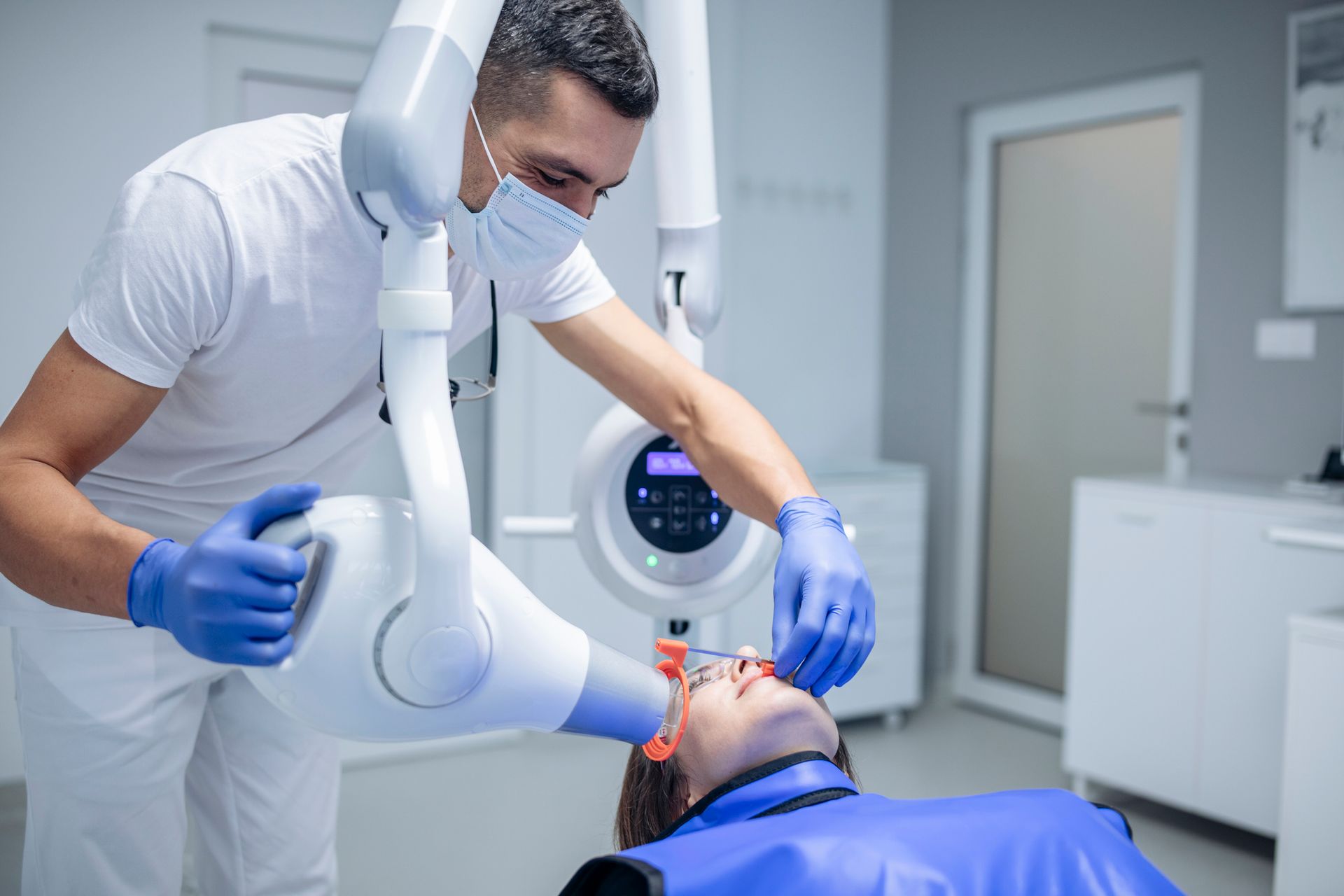 A dentist is taking an x-ray of a patient 's teeth in a dental office.