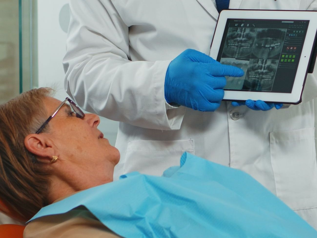 A dentist is looking at an x-ray of a patient 's teeth on a tablet.