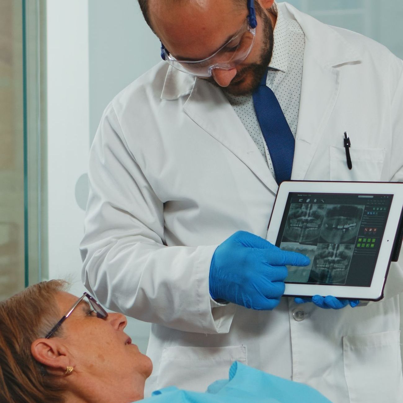 A dentist is looking at an x-ray on a tablet