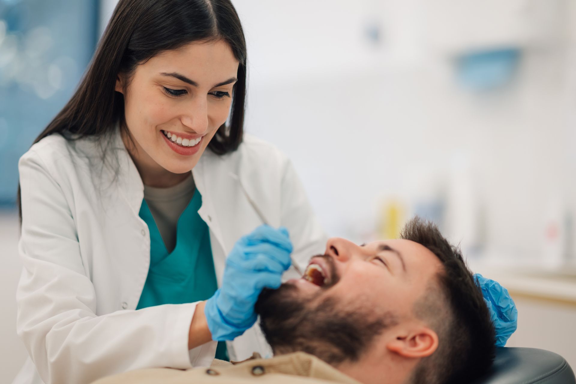 Dentist examining a patient's mouth with a mirror in an office setting.