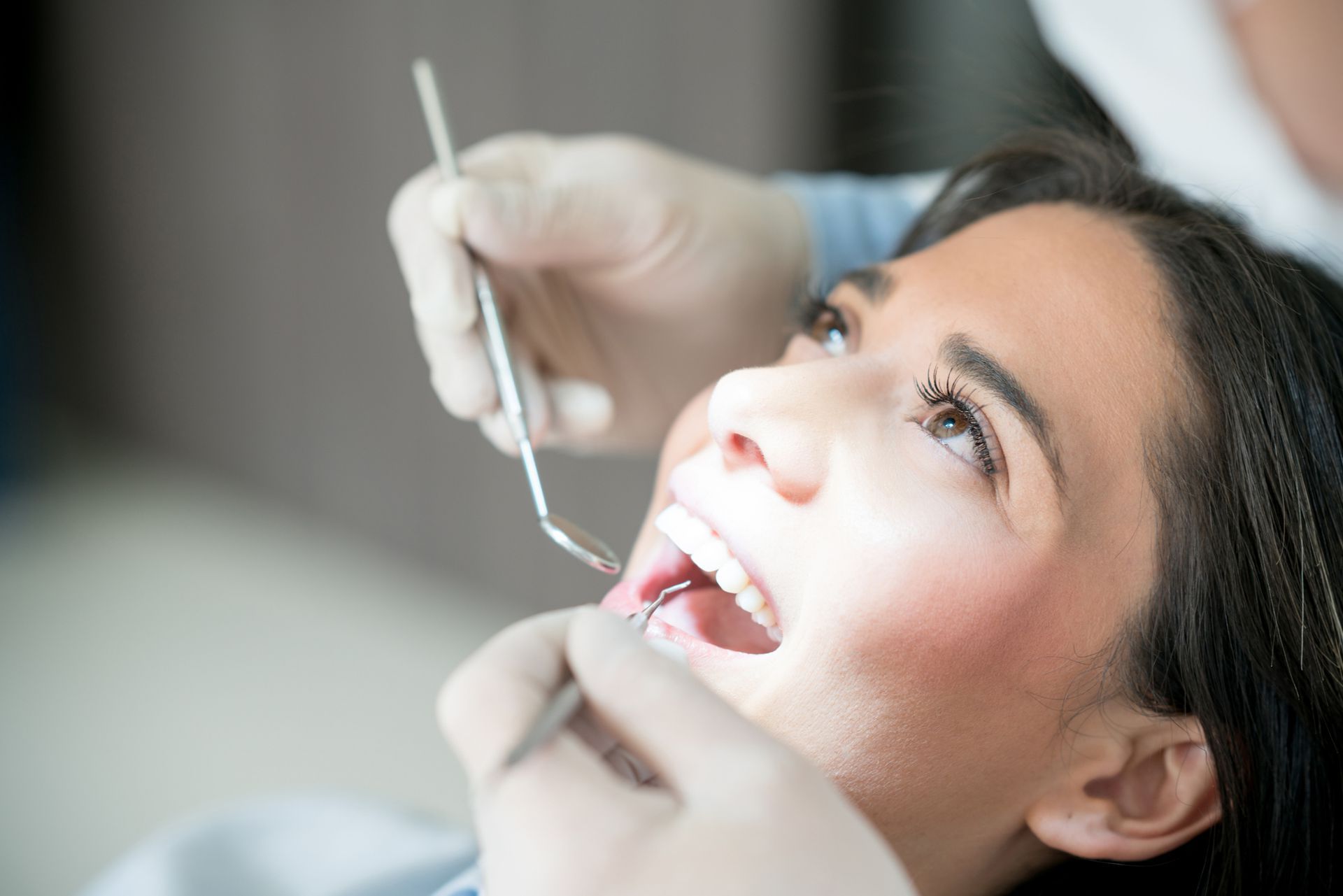 A woman is getting her teeth examined by a dentist.
