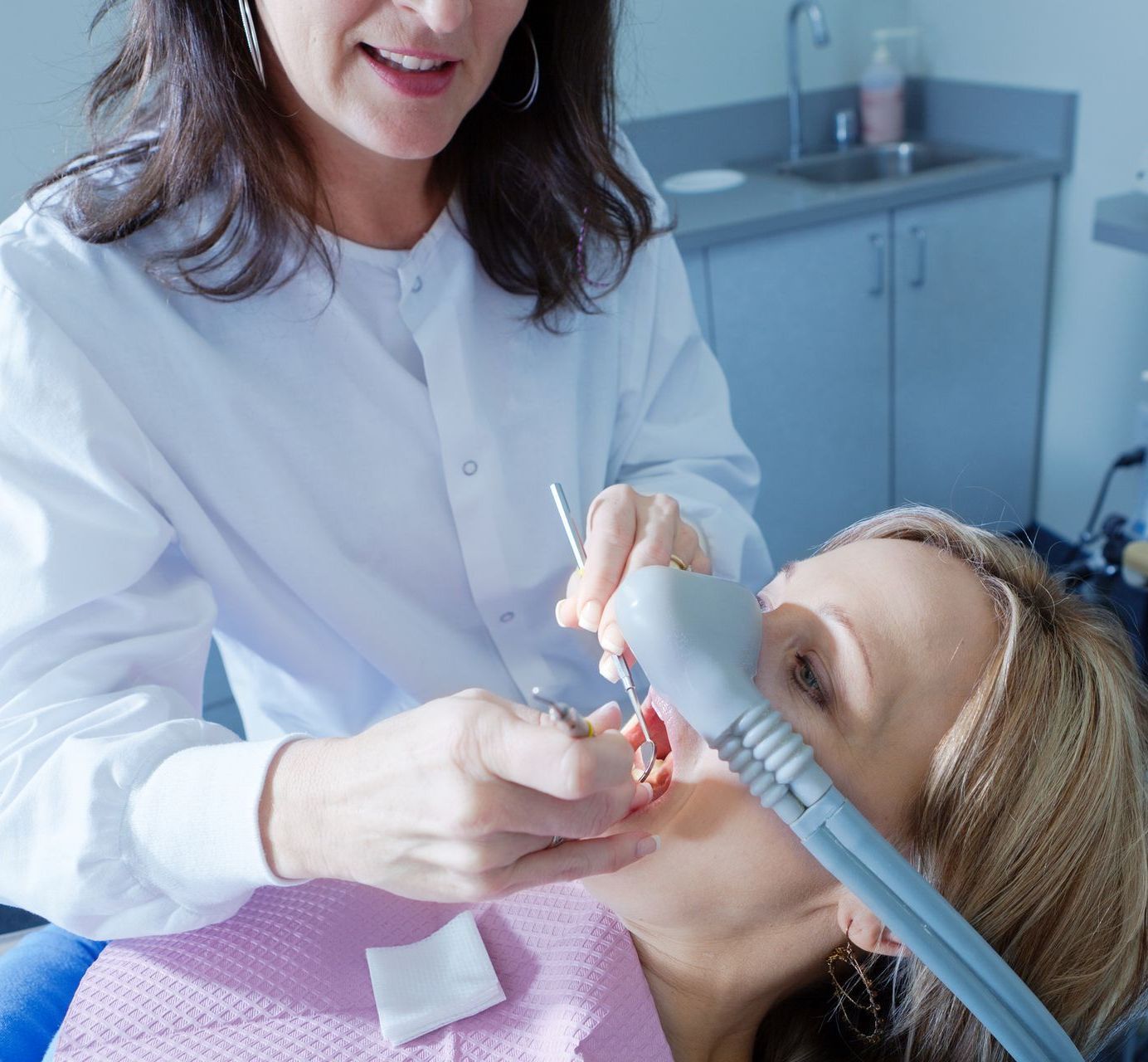 A woman is getting her teeth examined by a dentist