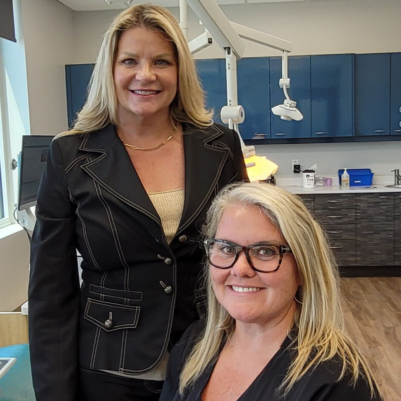 Two women are standing next to each other in a dental office.