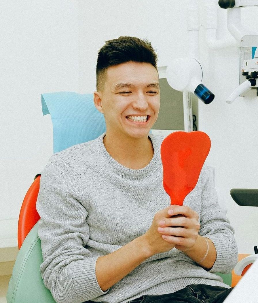 A man is smiling while looking at his teeth in a mirror