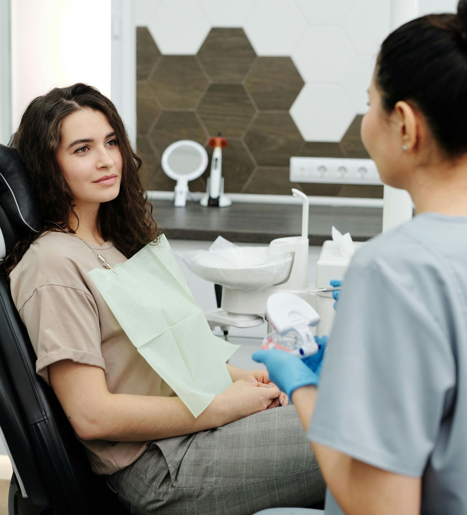A woman is sitting in a dental chair talking to a dentist.