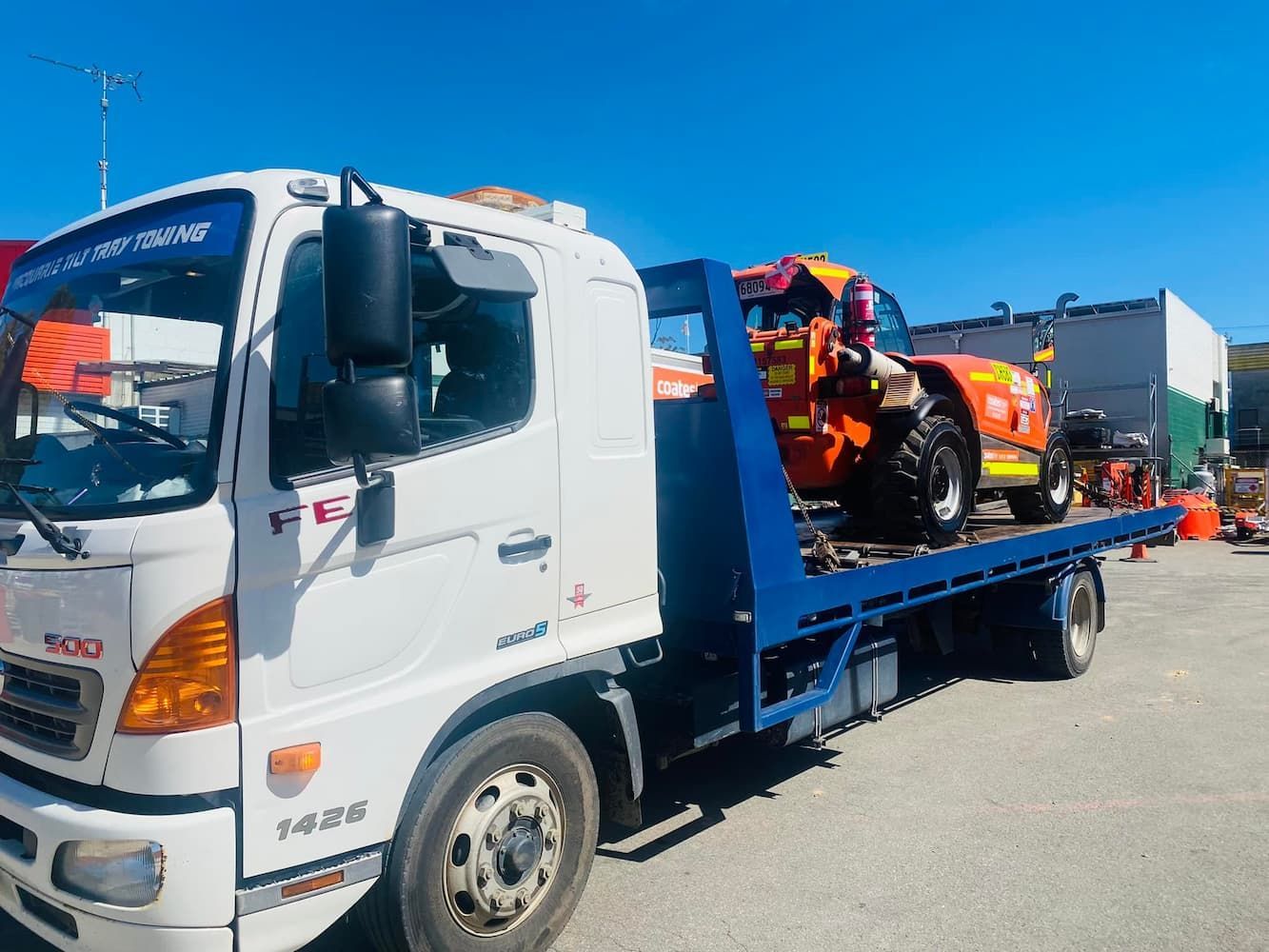 Truck Carrying Orange Tractor — Port Macquarie Tilt Tray Towing in Wauchope, NSW
