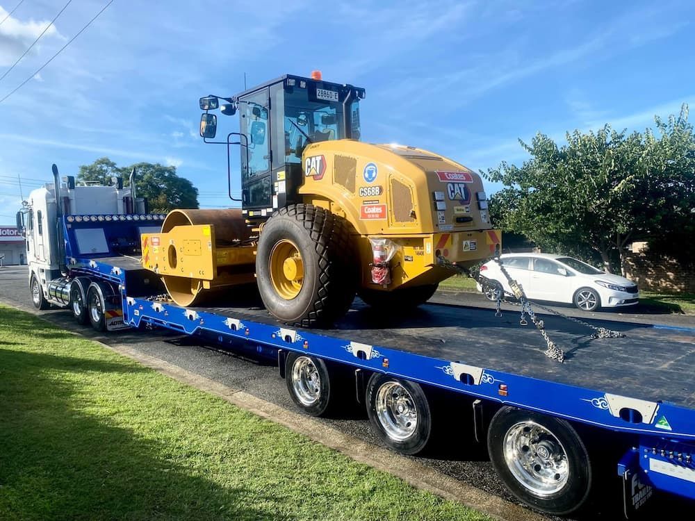 Heavy CAT Road Roller Firmly Secured on the Truck — Port Macquarie Tilt Tray Towing in Telegraph Point, NSW
