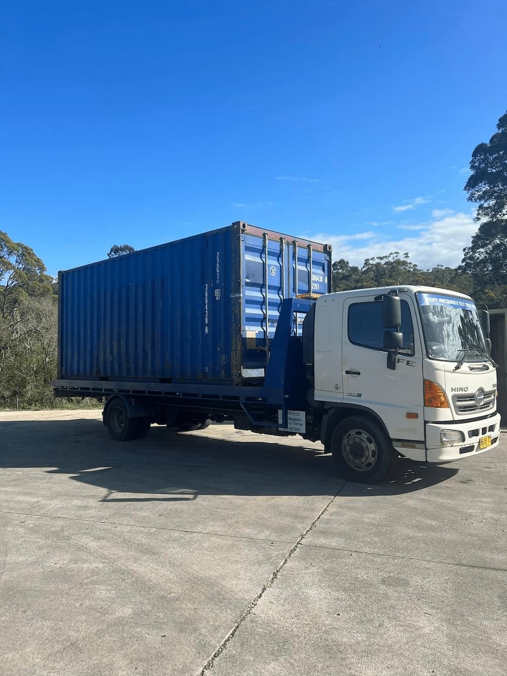 A white Truck Parked With Blue Container on a Cemented Parking Space — Port Macquarie Tilt Tray Towing in Telegraph Point, NSW