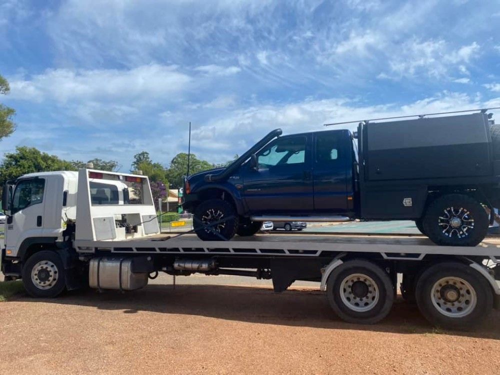 A Black Truck is Sitting on Top of a Flatbed Tow Truck — Port Macquarie Tilt Tray Towing in Newcastle, NSW