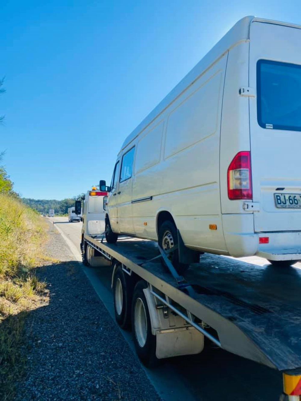 A White Van is Being Towed by a Tow Truck — Port Macquarie Tilt Tray Towing in Port Macquarie, NSW