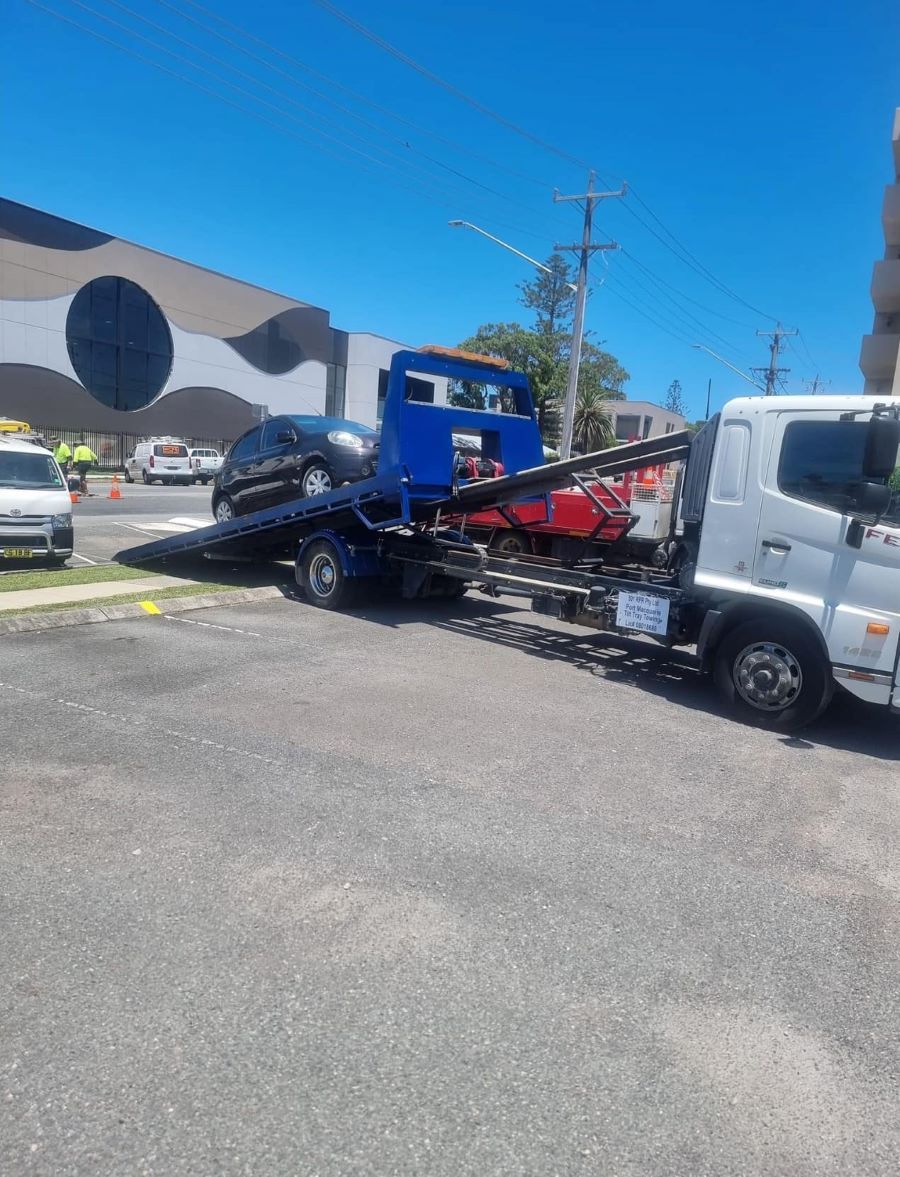 A Tow Truck is Towing a Car in a Parking Lot — Port Macquarie Tilt Tray Towing in Wauchope, NSW