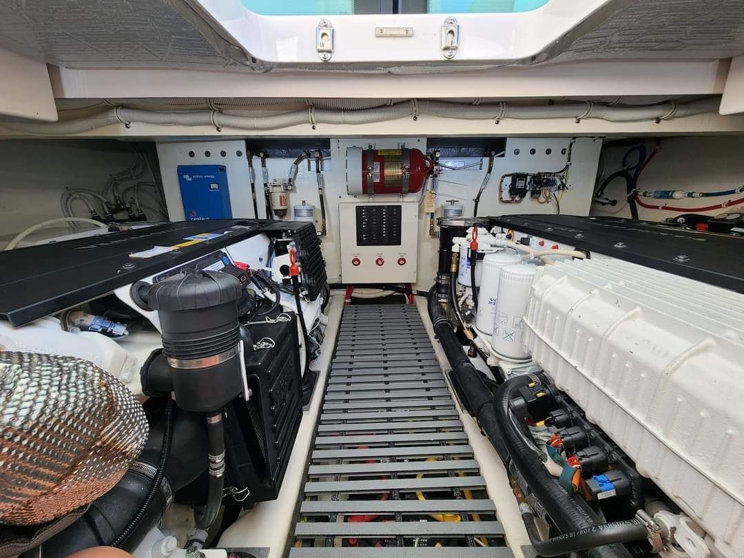 Interior view of a boat engine room with two large engines, various wires, and a central walkway.