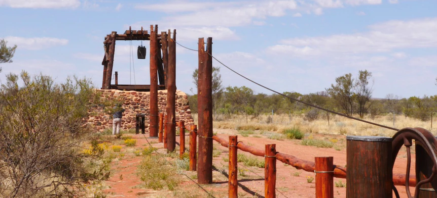 A wooden fence surrounds a stone building in the middle of a desert.