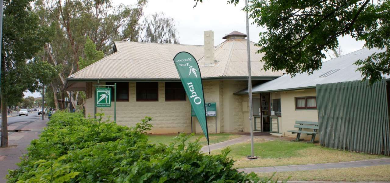 A white building with a green flag that says open on it