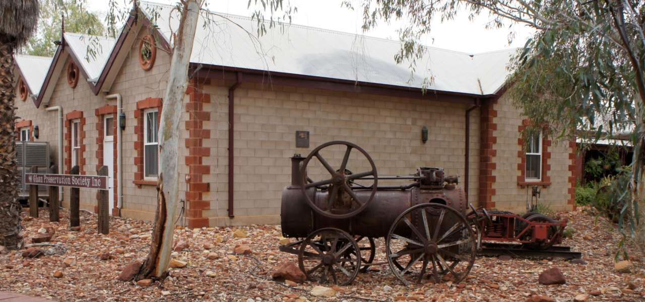 An old wagon is parked in front of a brick building.