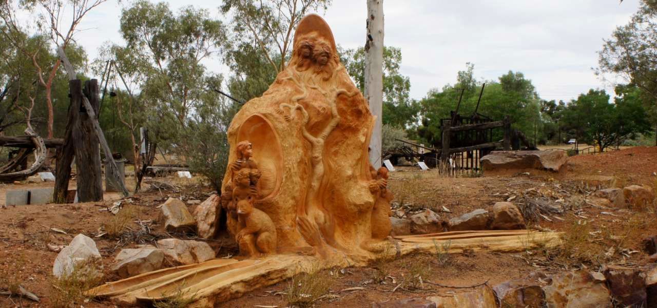A large piece of wood is sitting in the middle of a dirt field.