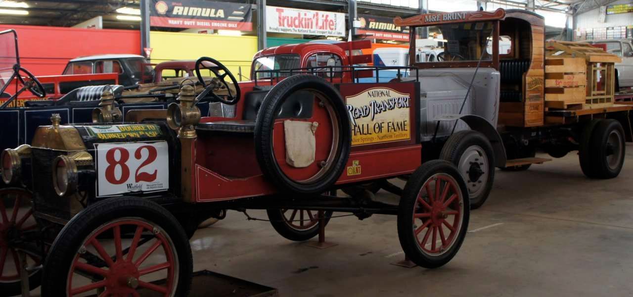 A red car with the number 82 on the side is parked next to a yellow truck.