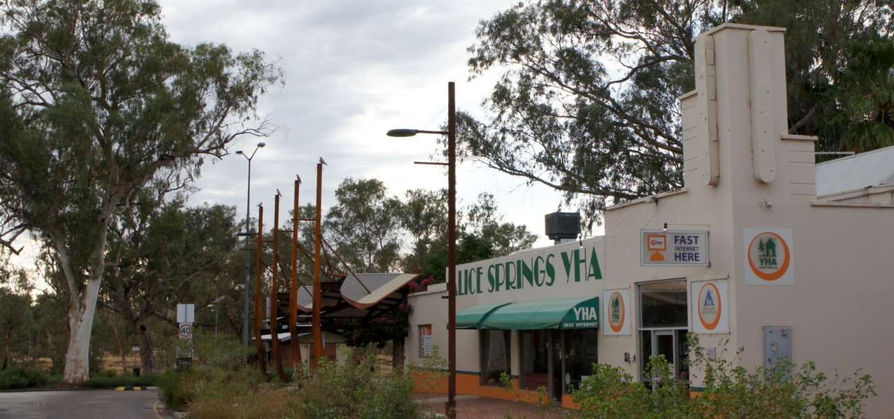 A white building with a green awning is surrounded by trees.