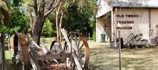 A wooden wagon wheel is sitting in front of a building.