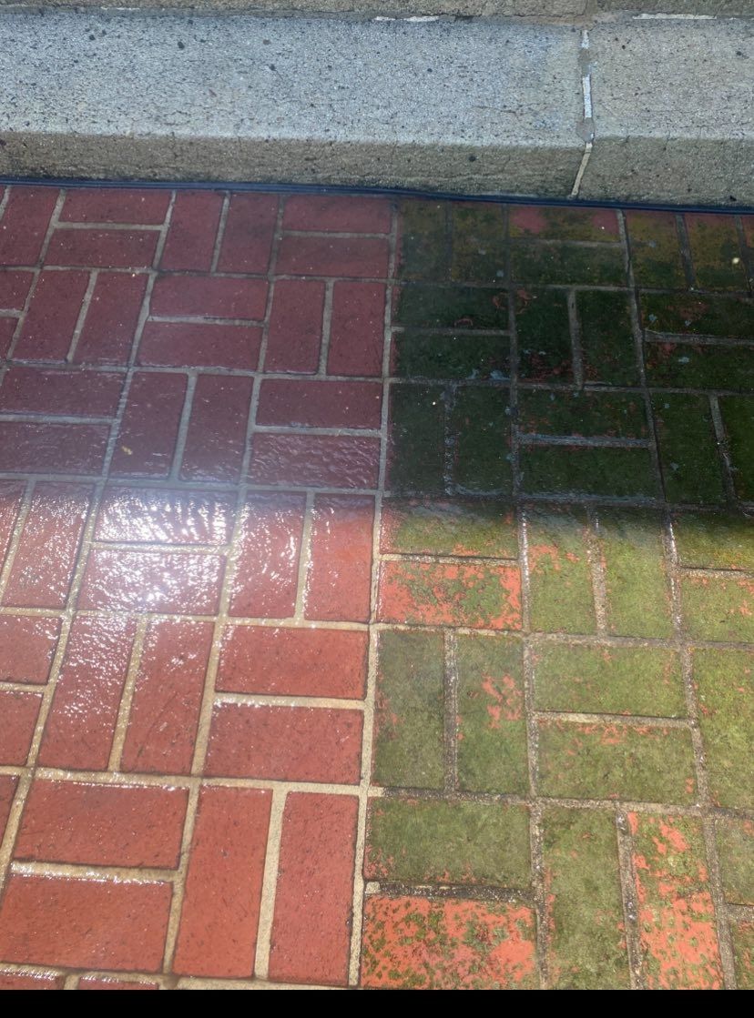 Red and green brick walkway beside a concrete wall, partly shaded by sunlight.