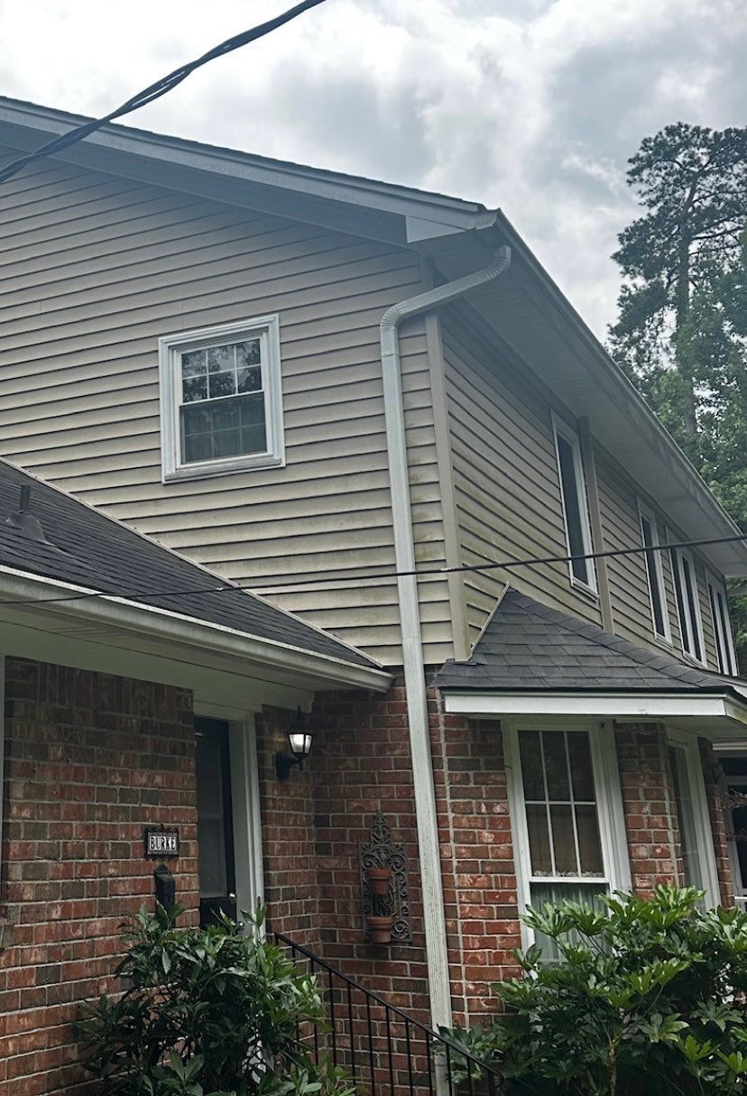 Two-story brick-and-siding house exterior with white-trimmed windows and a sloped roof