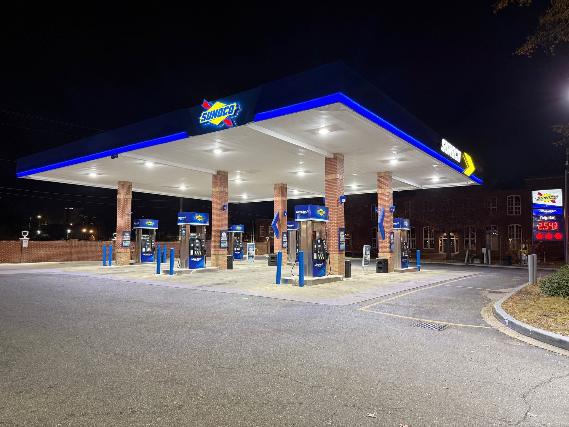 Gas station at night with blue-lit canopy and several fuel pumps on a mostly empty forecourt