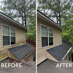 White rain gutter and downspout on a house roof with trees in the background